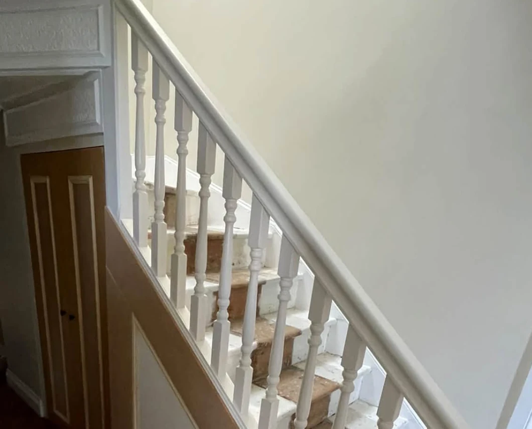 New staircase with turned spindles, painted panelling and fitted under-stairs cupboard doors by Brawls